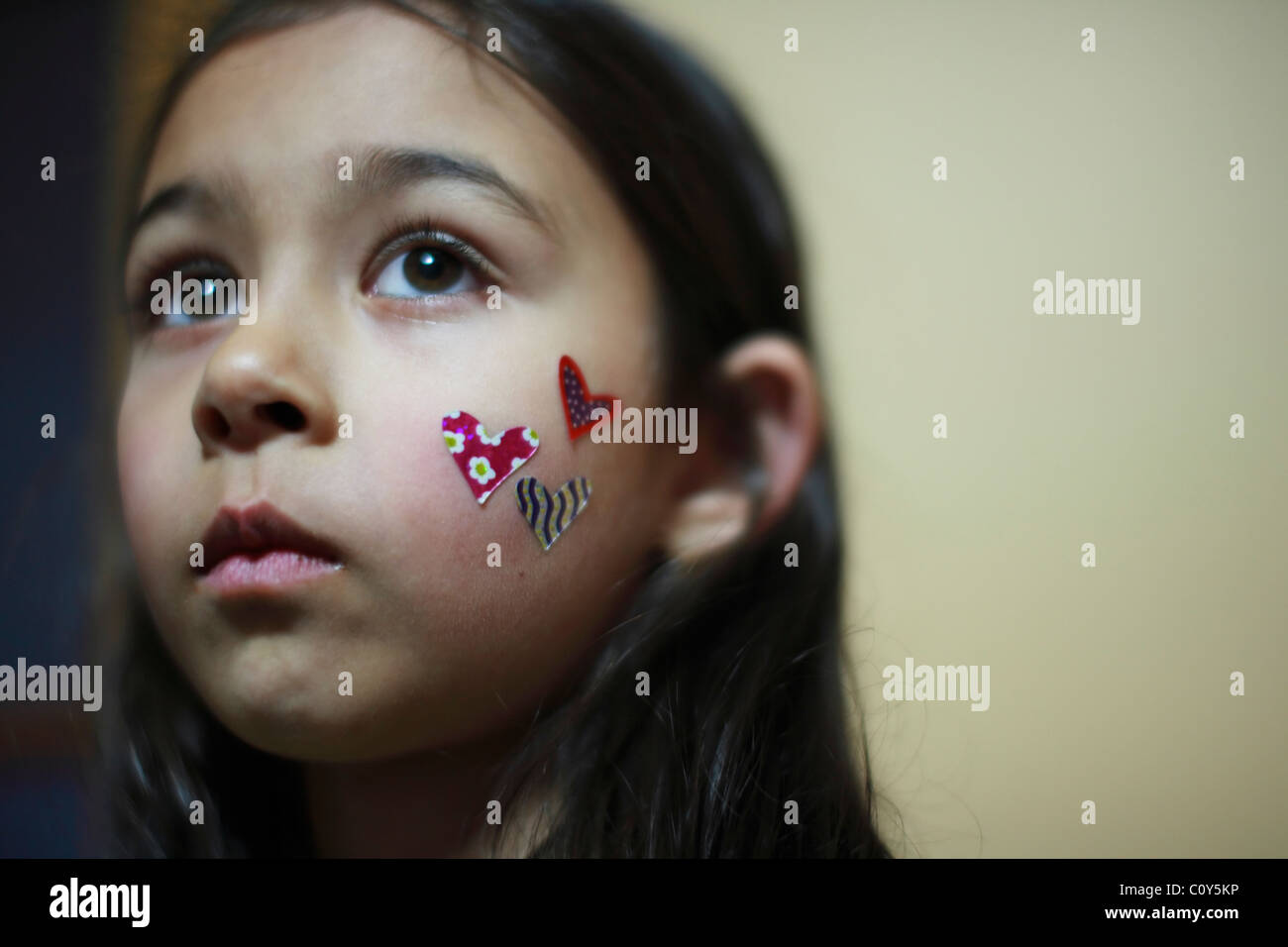 Ragazza con gli adesivi di cuore sulla guancia Foto Stock