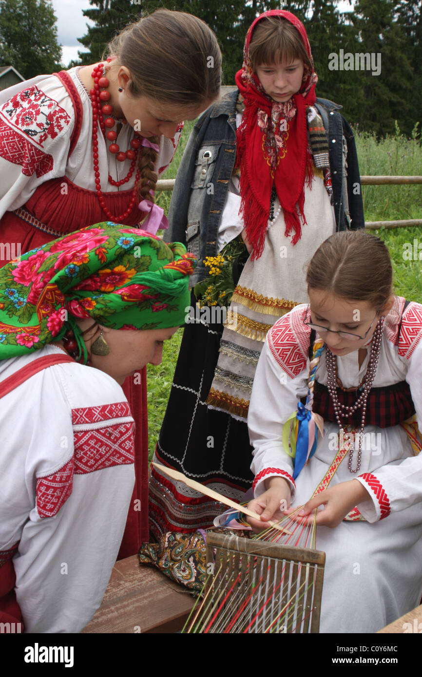 Ragazza, insegnamento tessitura tradizionale al festival di folklore a Pskov Regione. La Russia Foto Stock