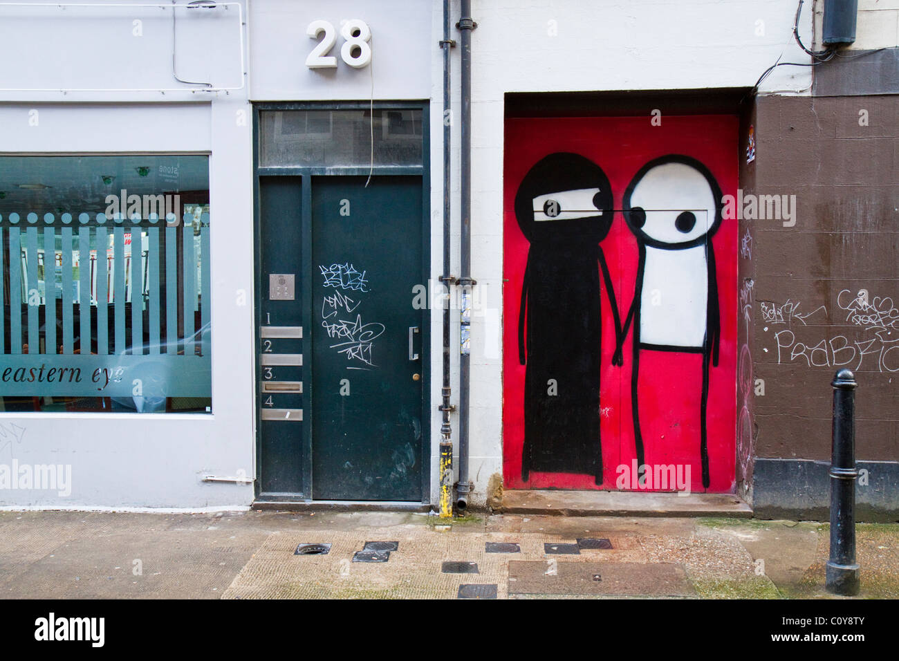 Vernice spray graffiti da artista di strada Stik in rappresentanza di un uomo e di una donna che indossa un burqa vicino a Brick Lane nella parte est di Londra, Regno Unito. Foto Stock