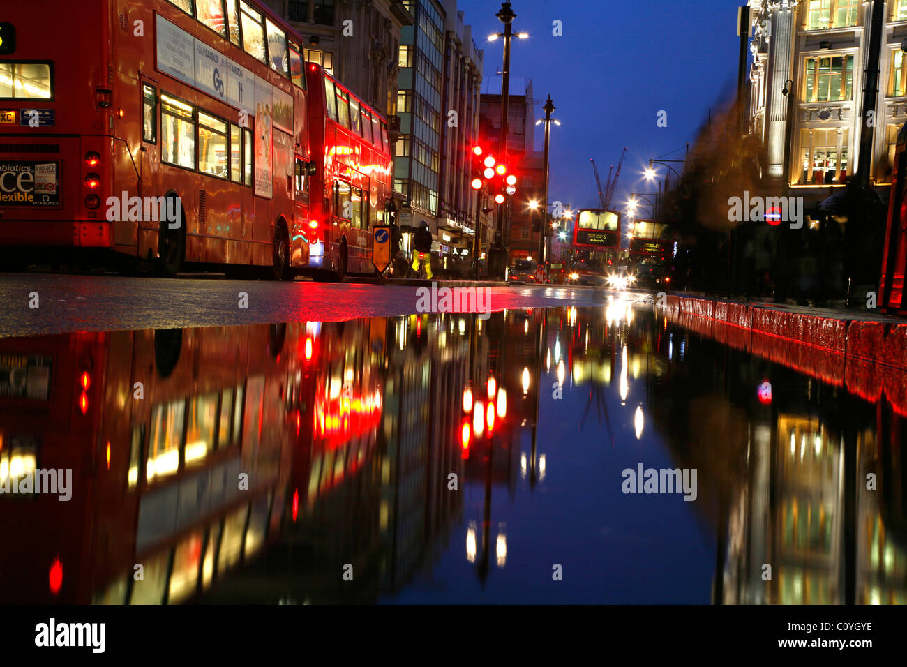 Visualizza in basso un wet Oxford Street per gli autobus in attesa di attraversare Oxford Circus, London, Regno Unito Foto Stock