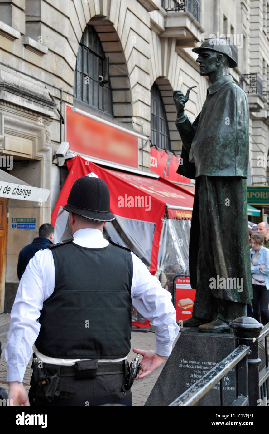 Battere poliziotto vista posteriore pattugliante zona turistica fuori Baker Street Station con Sherlock Holmes scultura oscurato segno negozio Londra Inghilterra Regno Unito Foto Stock