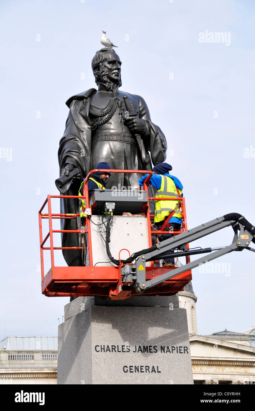 Pulitori su un cherry picker piattaforma di accesso per la pulizia la statua in bronzo di Charles James Napier seagull tenendo micky Trafalgar Square Londra Inghilterra REGNO UNITO Foto Stock