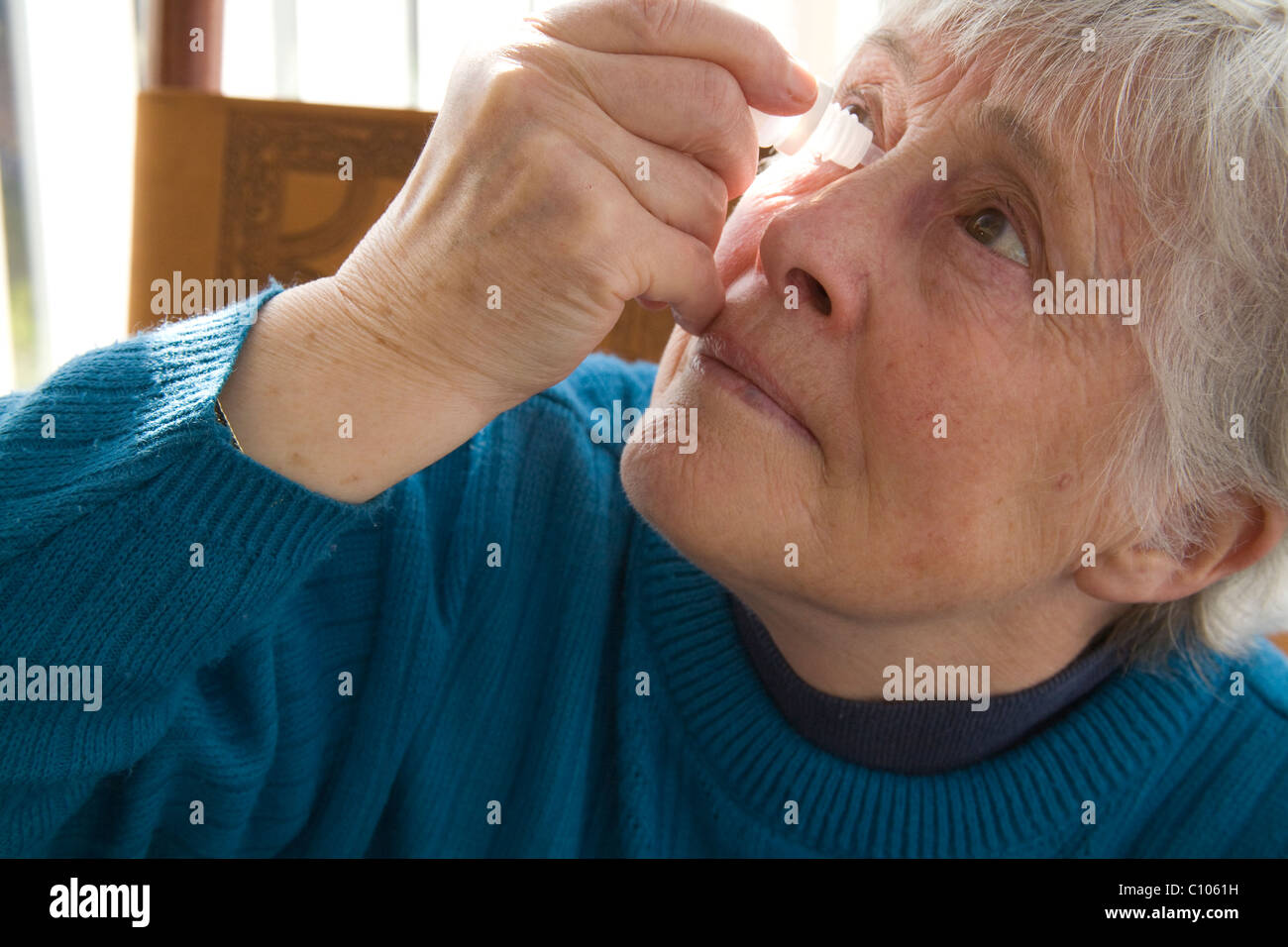 Close up donna anziana mettendo in anti istamina collirio per alleviare i sintomi del raffreddore da fieno Foto Stock