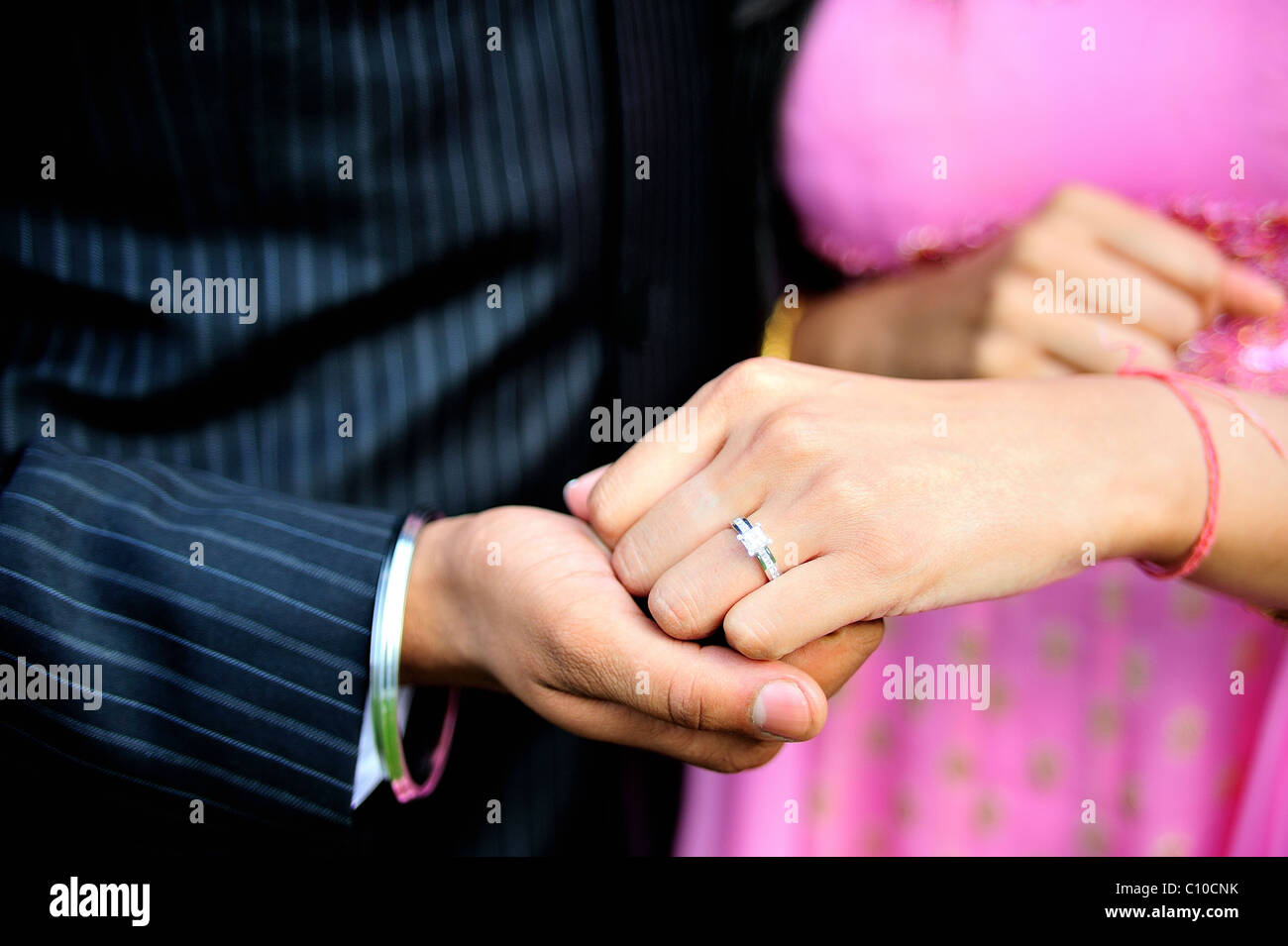 Un'immagine ravvicinata di due persone che si tengono per mano che mostra e anello di fidanzamento sono di origine indiana e Hindu Foto Stock