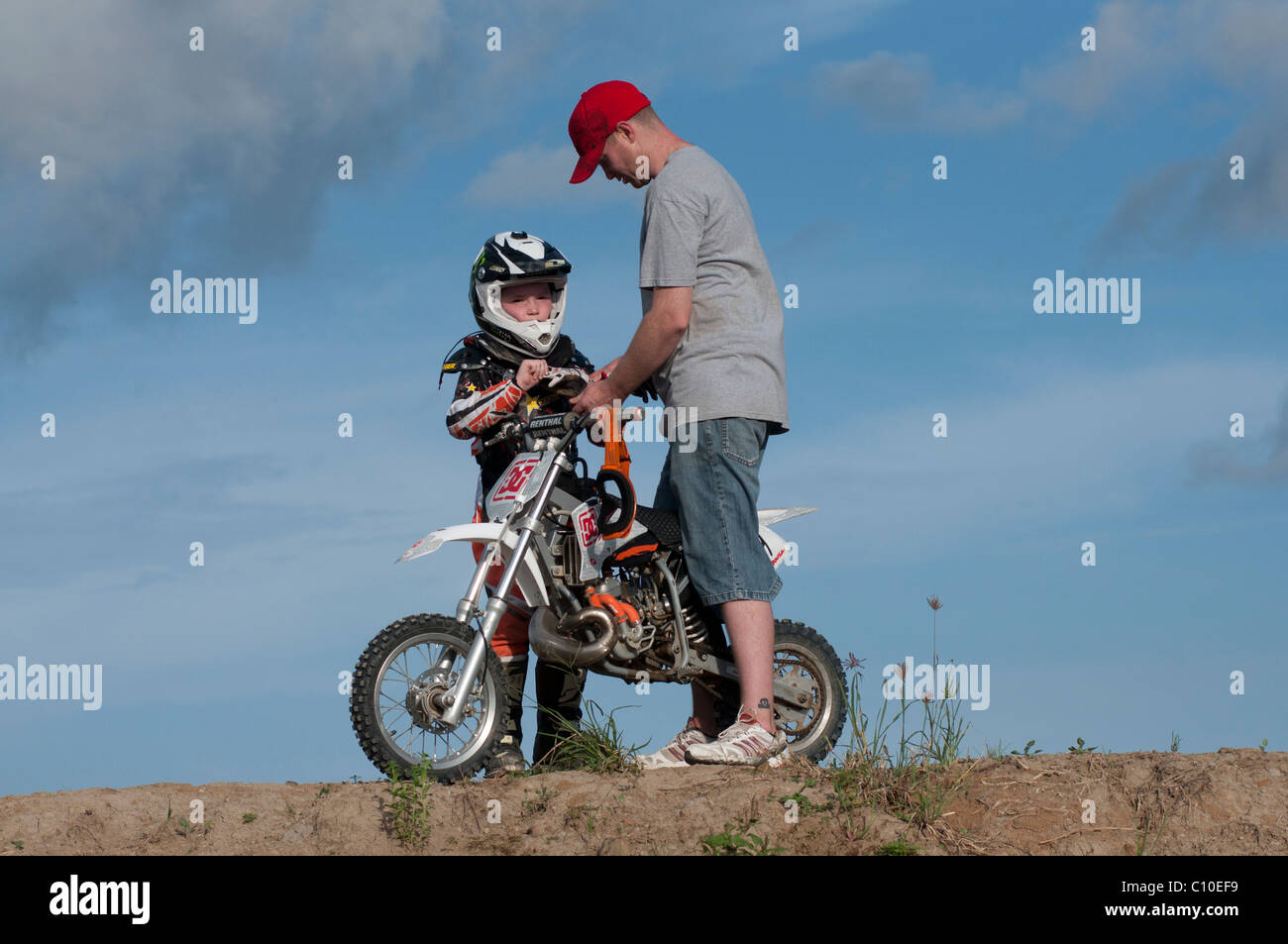 Un bambino di sei anni ragazzo con suo padre e motocross moto Foto Stock