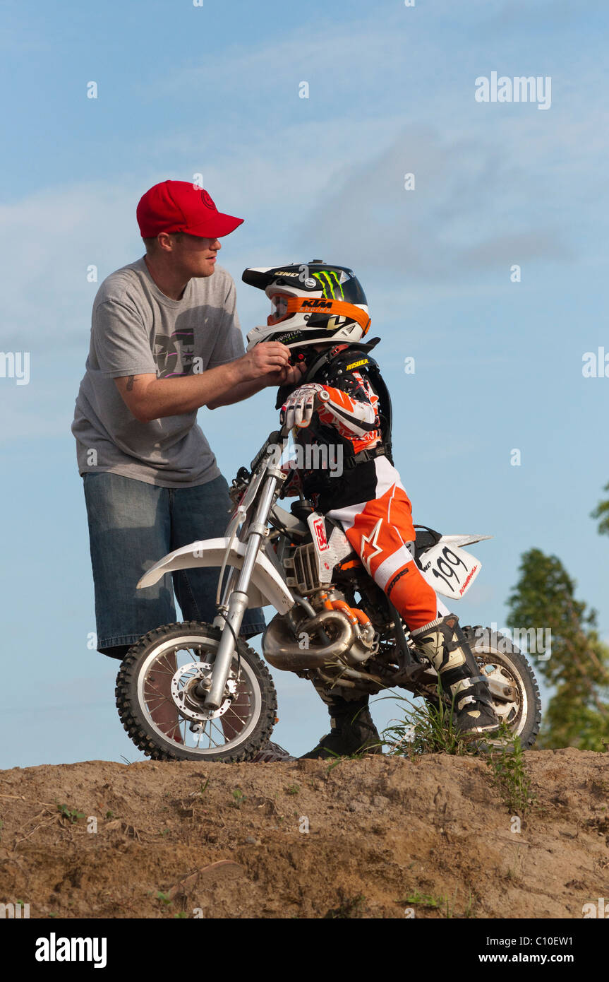 Un bambino di sei anni ragazzo con suo padre e motocross moto Foto Stock