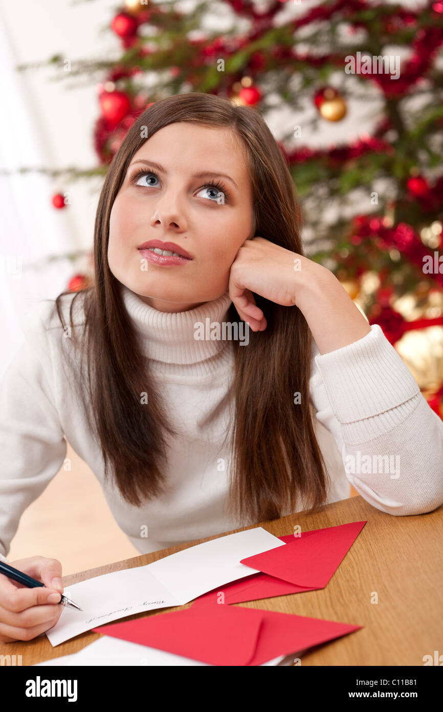 Giovane donna la scrittura di Natale carta nella parte anteriore della struttura ad albero Foto Stock