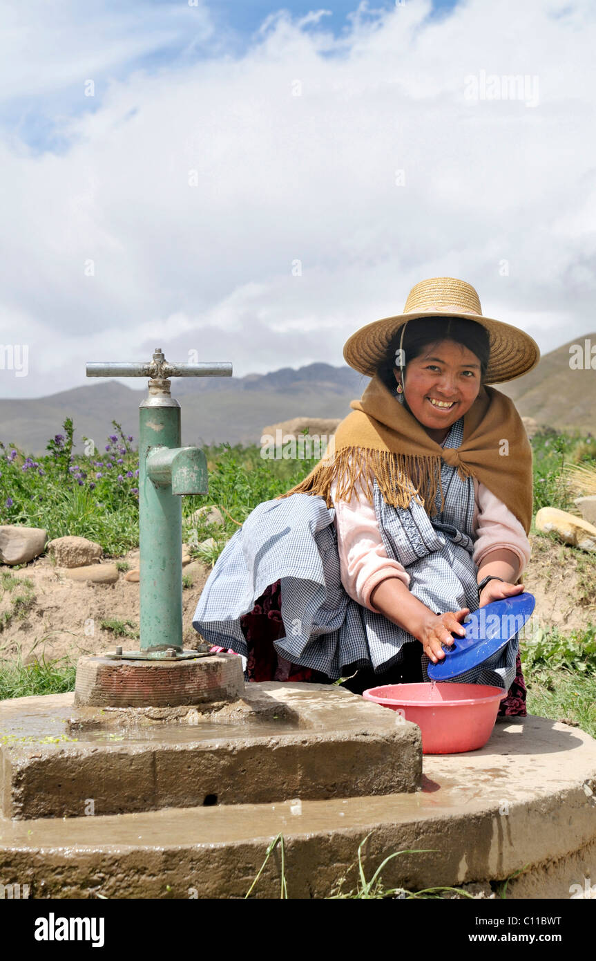 Le donne in abito tradizionale del quechua facendo piatti presso il pozzo, Altipiano boliviano highlands, Departamento Oruro, Bolivia Foto Stock
