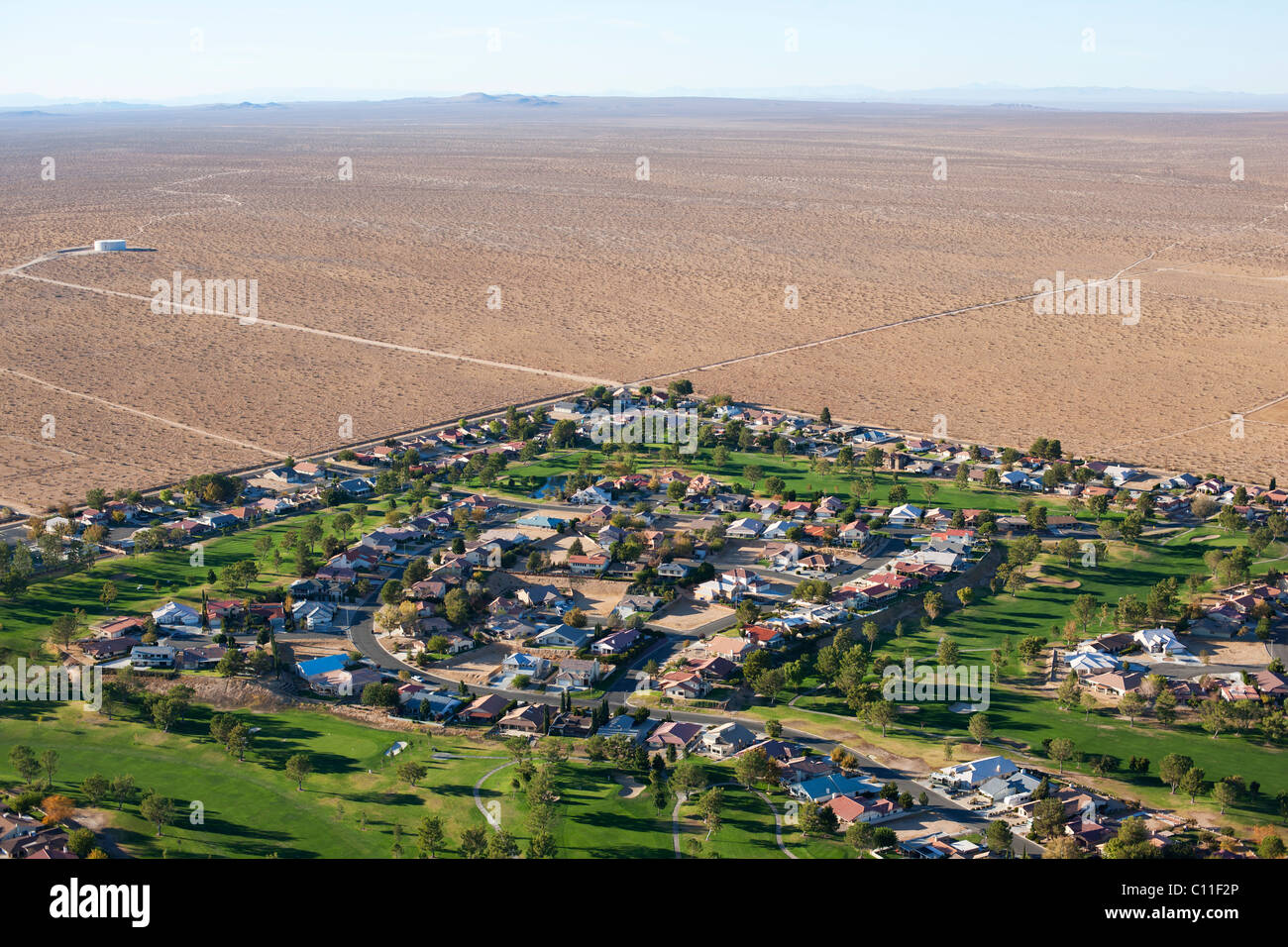 VISTA AEREA. Sviluppo di alloggi nel deserto di Mojave duro. Comunità non costituita di Helendale, San Bernardino County, California, USA. Foto Stock