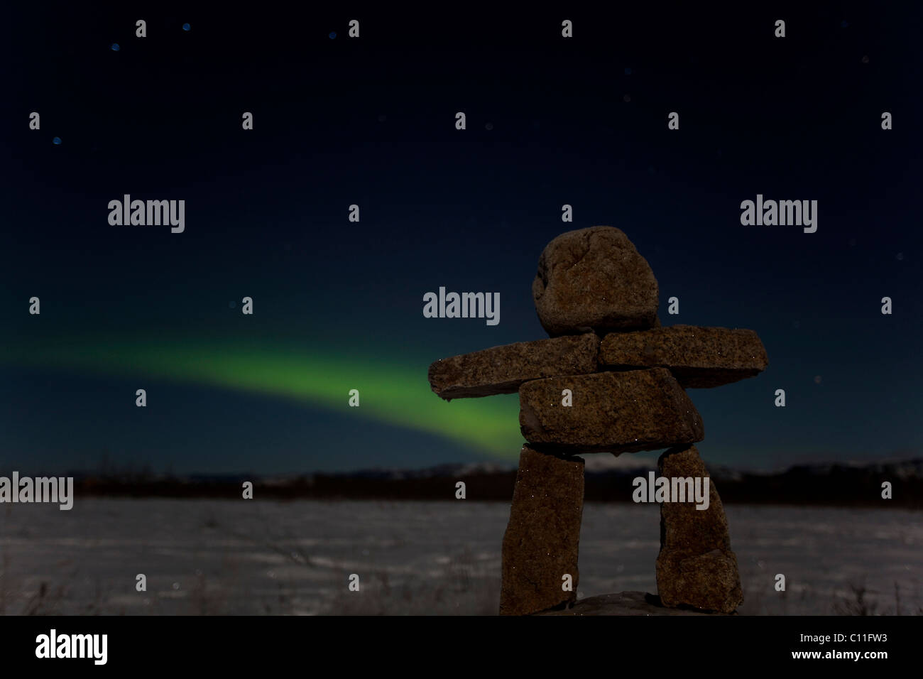 Inuit uomo di pietra, inukshuk, pietra landmark o cairn, verde Northern Lights luci polari (Aurora boreale), vicino a Whitehorse Foto Stock