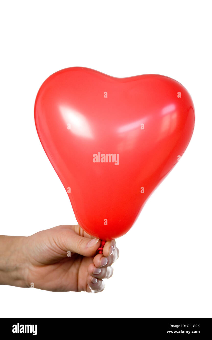 Un cuore palloncino a forma di detenute da una mano Foto Stock