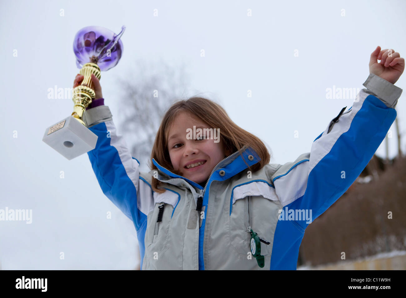 Ragazza, 9, rallegrandosi con un trofeo durante una cerimonia di premiazione Foto Stock