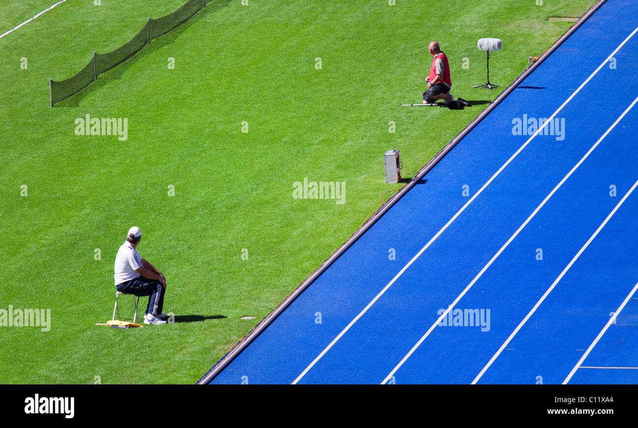 Fotografo e aiutanti sul prato di uno stadio sportivo Foto Stock