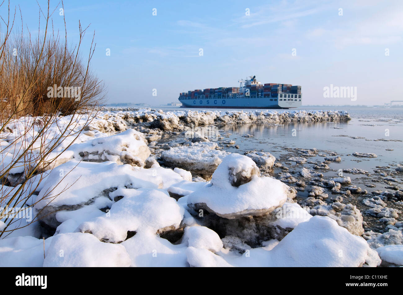 Un contenitore nave viaggia su wintery fiume Elba a Blankenese, Amburgo, Germania, Europa Foto Stock
