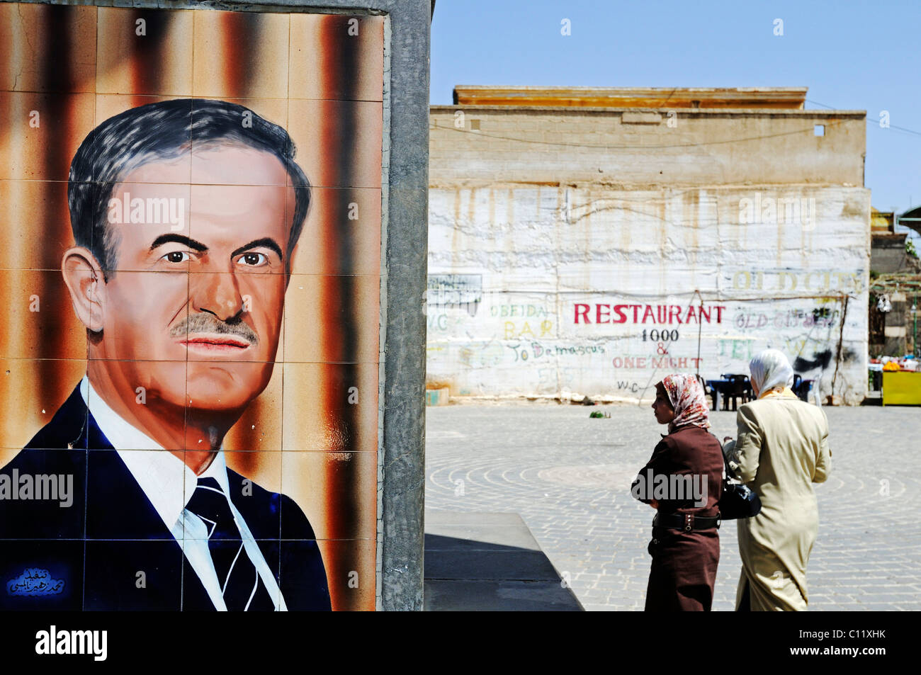 Piastrelle con un ritratto di ex presidente Hafez al Assad, e le donne con il velo, Bosra, Siria, Asia Foto Stock