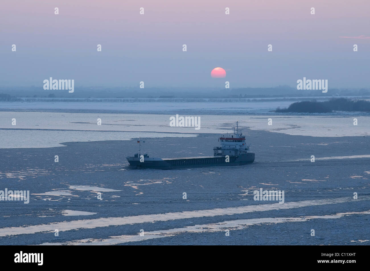 Una nave portacontainer in viaggio al tramonto sulla wintery fiume Elba a Blankenese, Amburgo, Germania, Europa Foto Stock