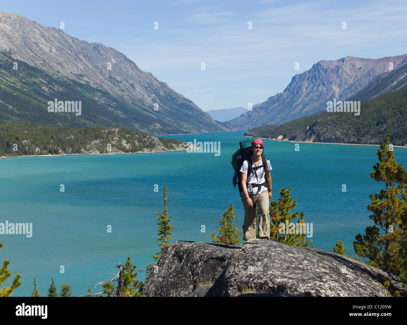 Giovane donna escursionismo, backpacking, escursionista con zaino, storico Chilkoot Pass, Chilkoot Trail, Lake Bennett dietro Foto Stock