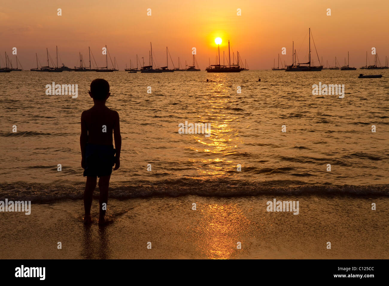 Il ragazzo, 6 anni, ammirando il tramonto sul Nai Han Beach, sull'Isola di Phuket, nel sud della Thailandia, Thailandia, Sud-est asiatico Foto Stock