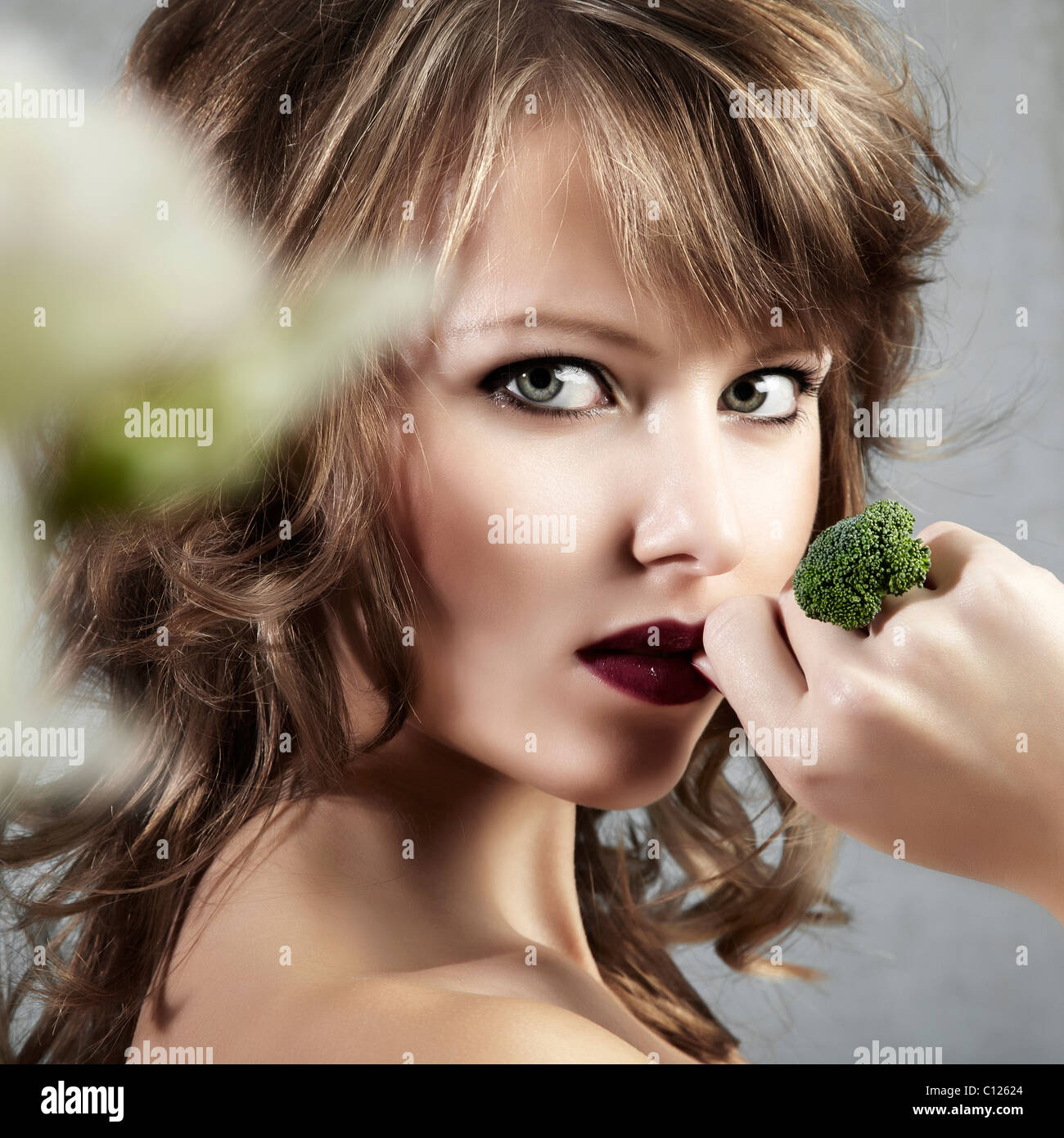 Lato ritratto di una giovane donna che mantiene la sua mano con un anello di broccoli seductively per la sua bocca, gioielli Foto Stock