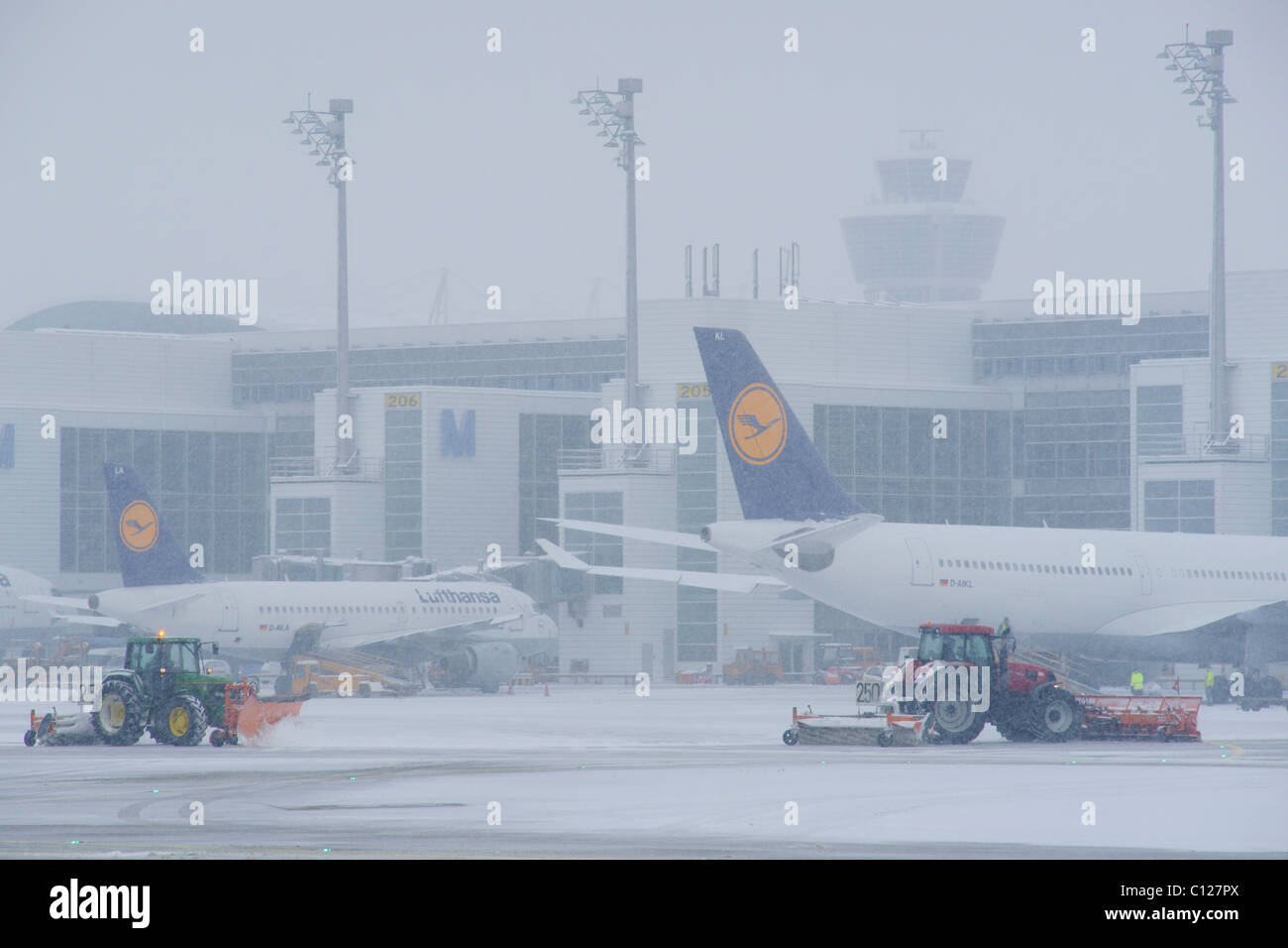 Neve in inverno e rimozione della neve con i trattori, aeromobili, di rullaggio, torre di controllo, terminale 2, East grembiule, Aeroporto di Monaco di Baviera, MUC, Bavaria Foto Stock