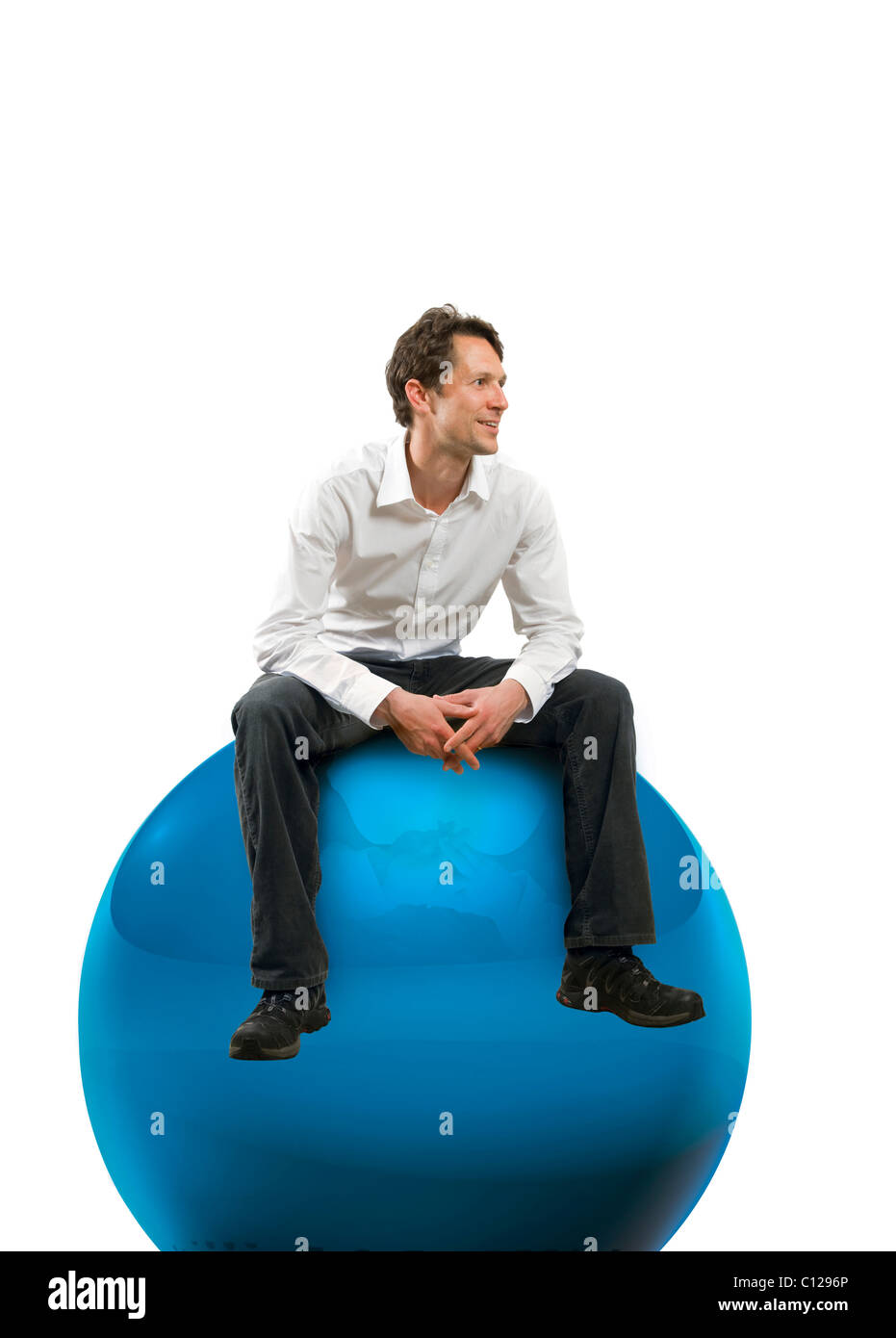 Giovane con una camicia bianca seduto su una grande sfera blu Foto Stock