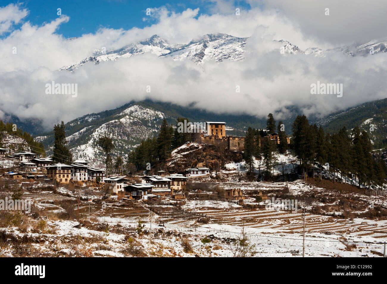 Immagine orizzontale dell'Himalaya montagne dopo una nevicata con un antico dzong bhutanesi su una collina in primo piano Foto Stock