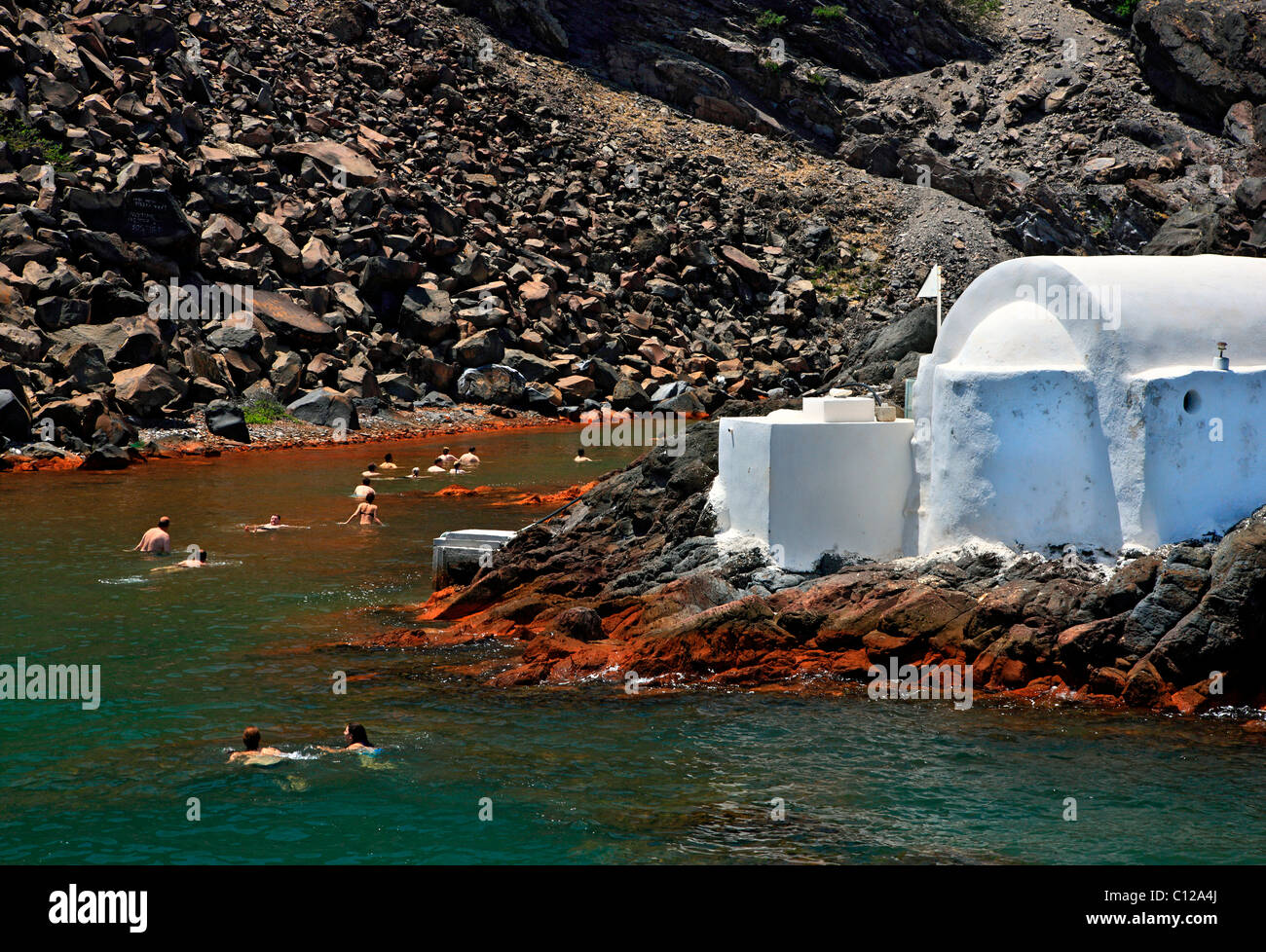 Le persone a nuotare in acque termali di Palaia ("old") Kammeni isola nel cuore della caldera di Santorini, Grecia. Foto Stock