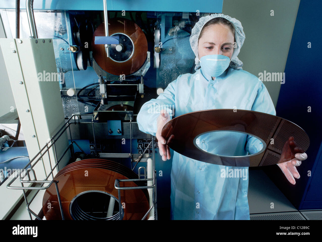 Tecnico in un ambiente clean room ispeziona il rivestimento su un vassoio utilizzato nella fabbricazione di unità disco rigido del computer i dischi. Foto Stock