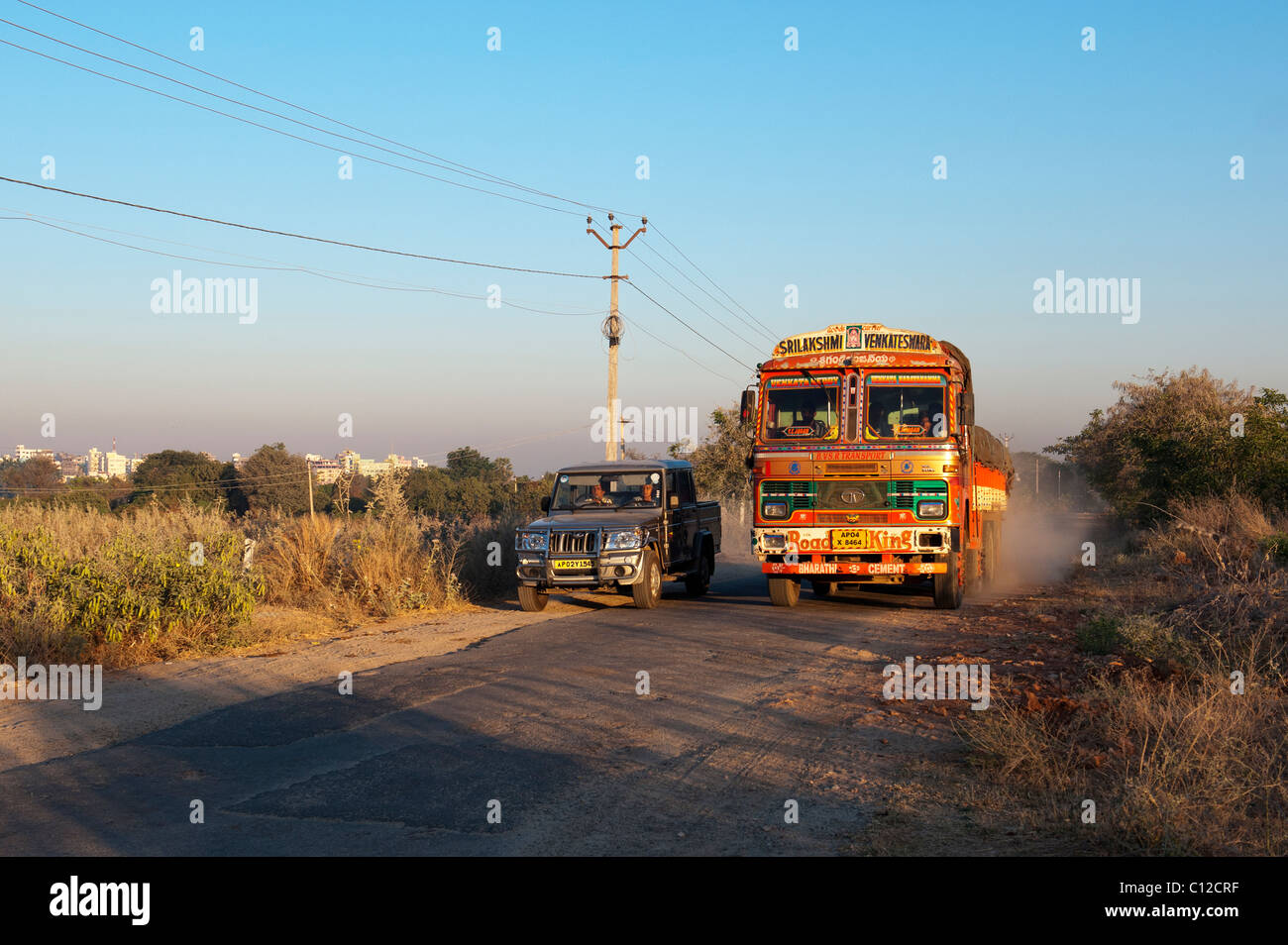 India autocarro di trasporto percorrendo una strada rischia di essere superato da un veicolo 4x4 nella campagna indiana. Andhra Pradesh, India Foto Stock