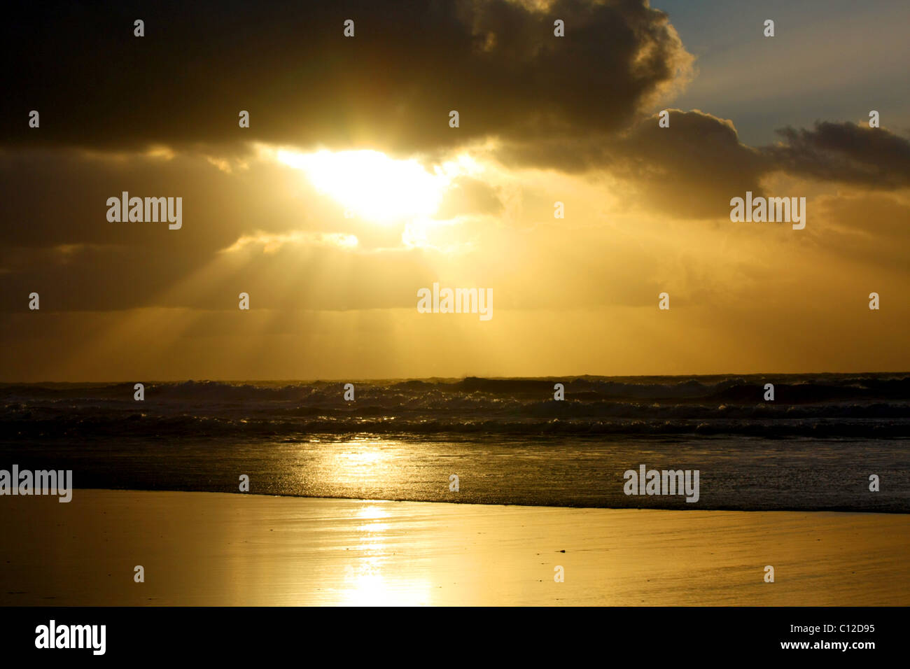 40,151.06066a raggi di sole raggi di sole nuvole scure strati cloud golden bagliore di luce del sole splendente su Ocean Waves Beach. Foto Stock