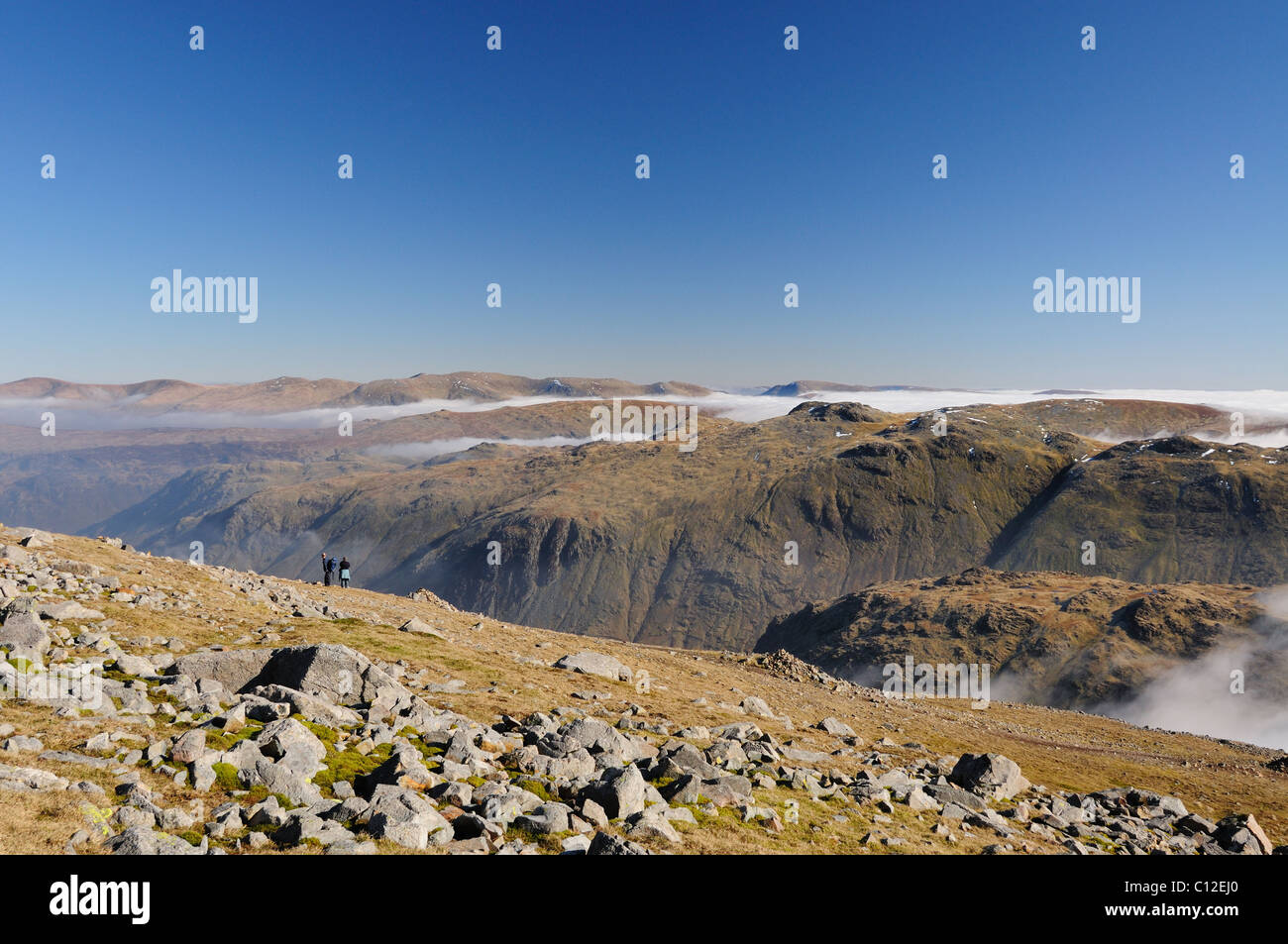 Walkers sul grande timpano che si affacciava su Seathwaite cadde e Glaramara su una soleggiata giornata di primavera nel Lake District inglese Foto Stock