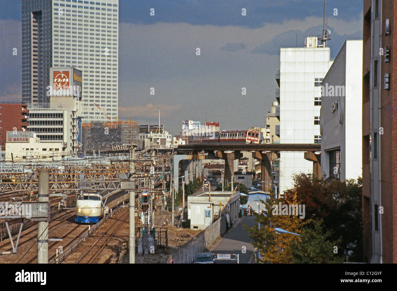 Il treno superveloce Shinkansen avvicinandosi alla stazione di Tokyo locale con un treno monorotaia sopra il ponte, c.1982 Foto Stock