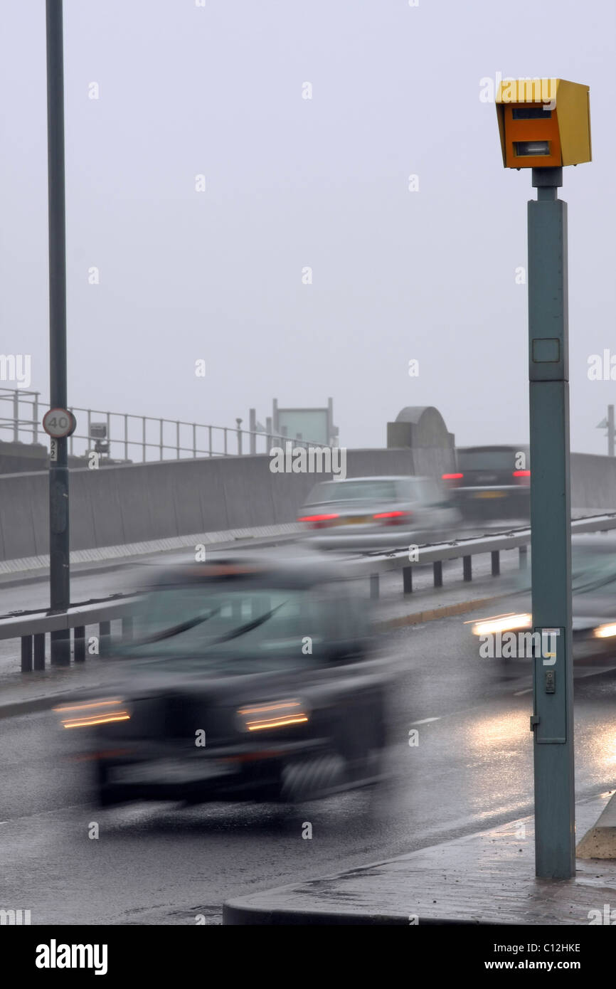 Un taxi e autovetture passando a un autovelox sul bagnato giorno sordo a Londra in Inghilterra Foto Stock
