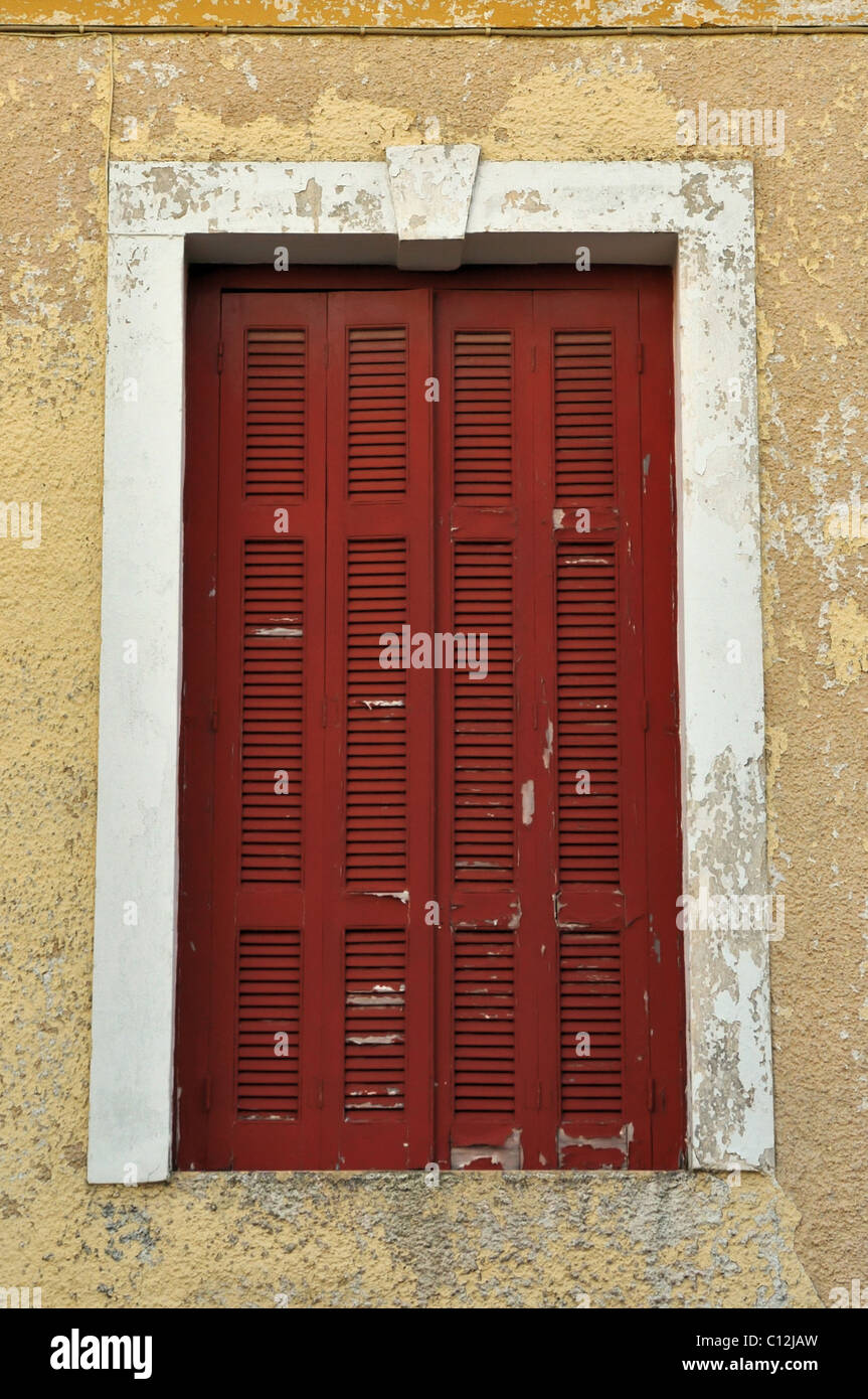 La finestra rossa otturatore ed alterò tagliò vernice parete. Foto Stock