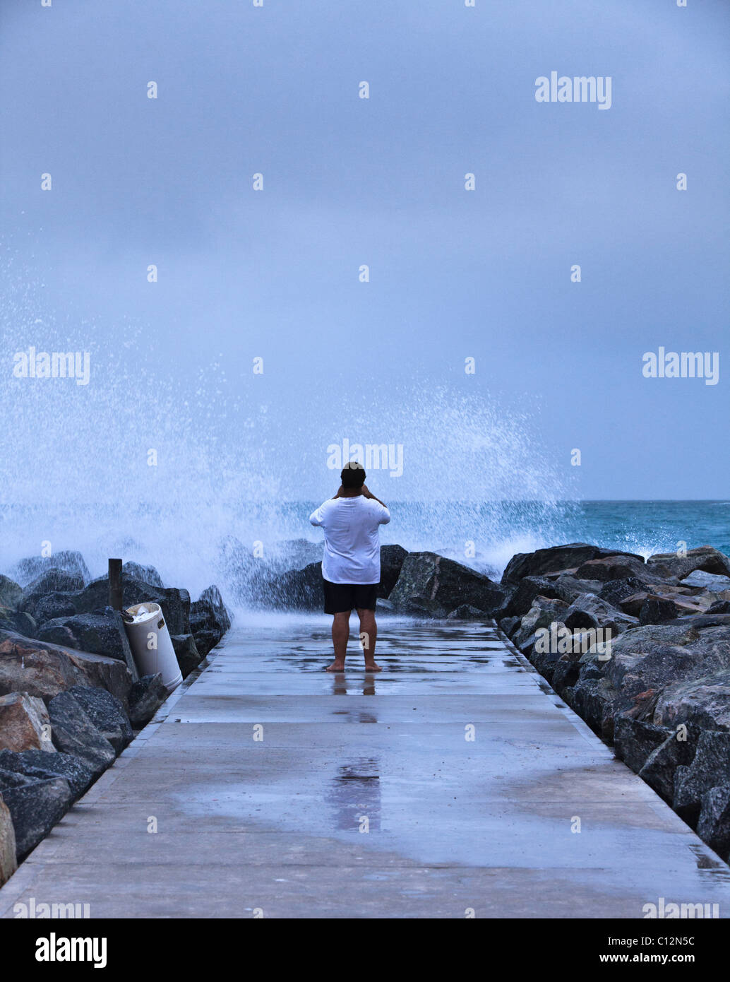 L'uomo prendendo fotografie delle onde provenienti da groyne. Le grandi onde sono stati provocati dal ciclone Bianca Foto Stock