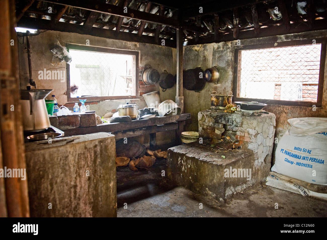 Una tradizionale cucina Balinese in un piccolo villaggio dispone di un forno a legna, un sacco di riso e un pavimento di immondizia. Foto Stock