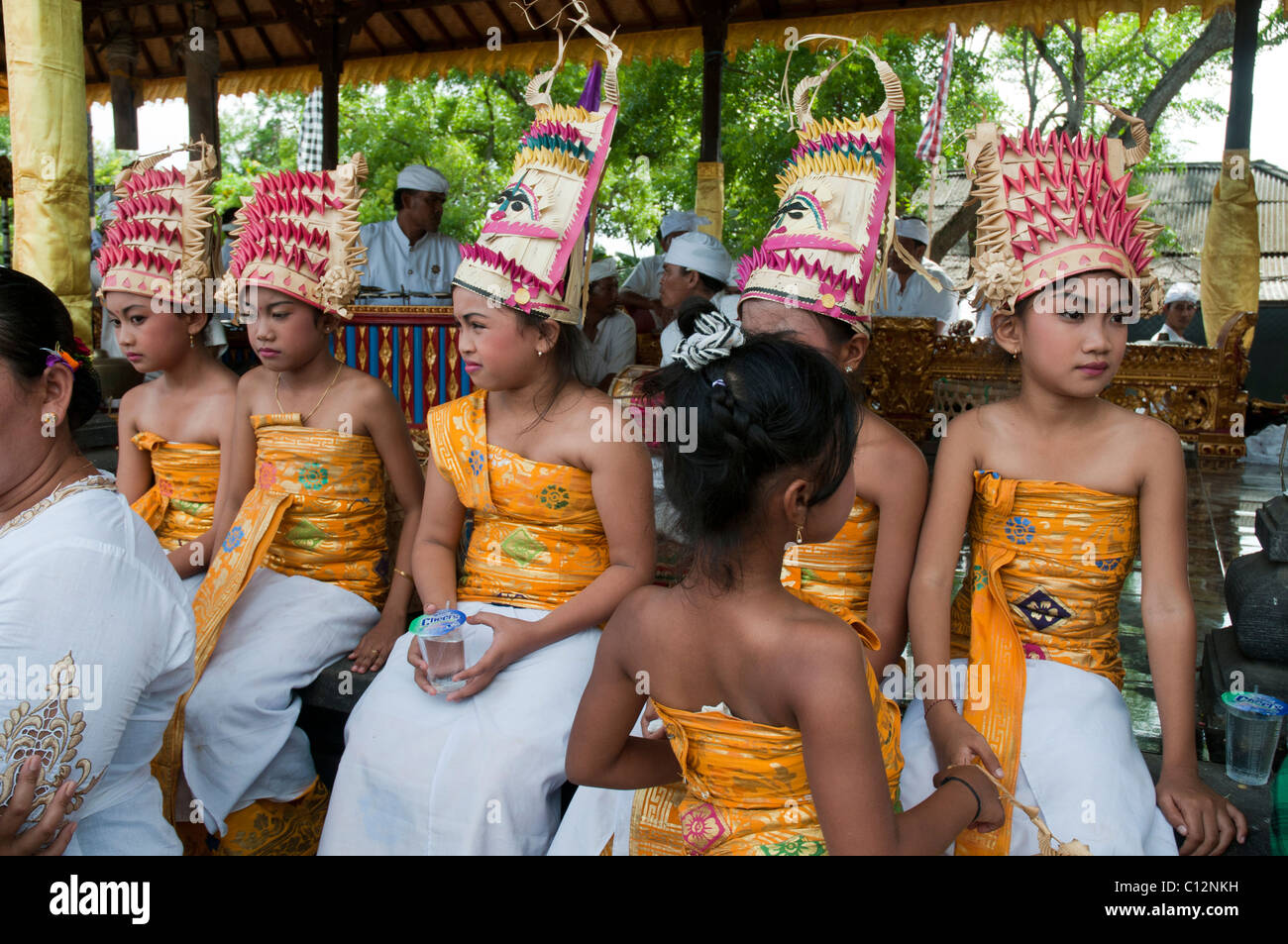 Giovane ragazza che indossa il costume tradizionale di una ballerina del tempio che guarda uno spettacolo in un festival del tempio a Padang Bai, Bali, Indonesia Foto Stock