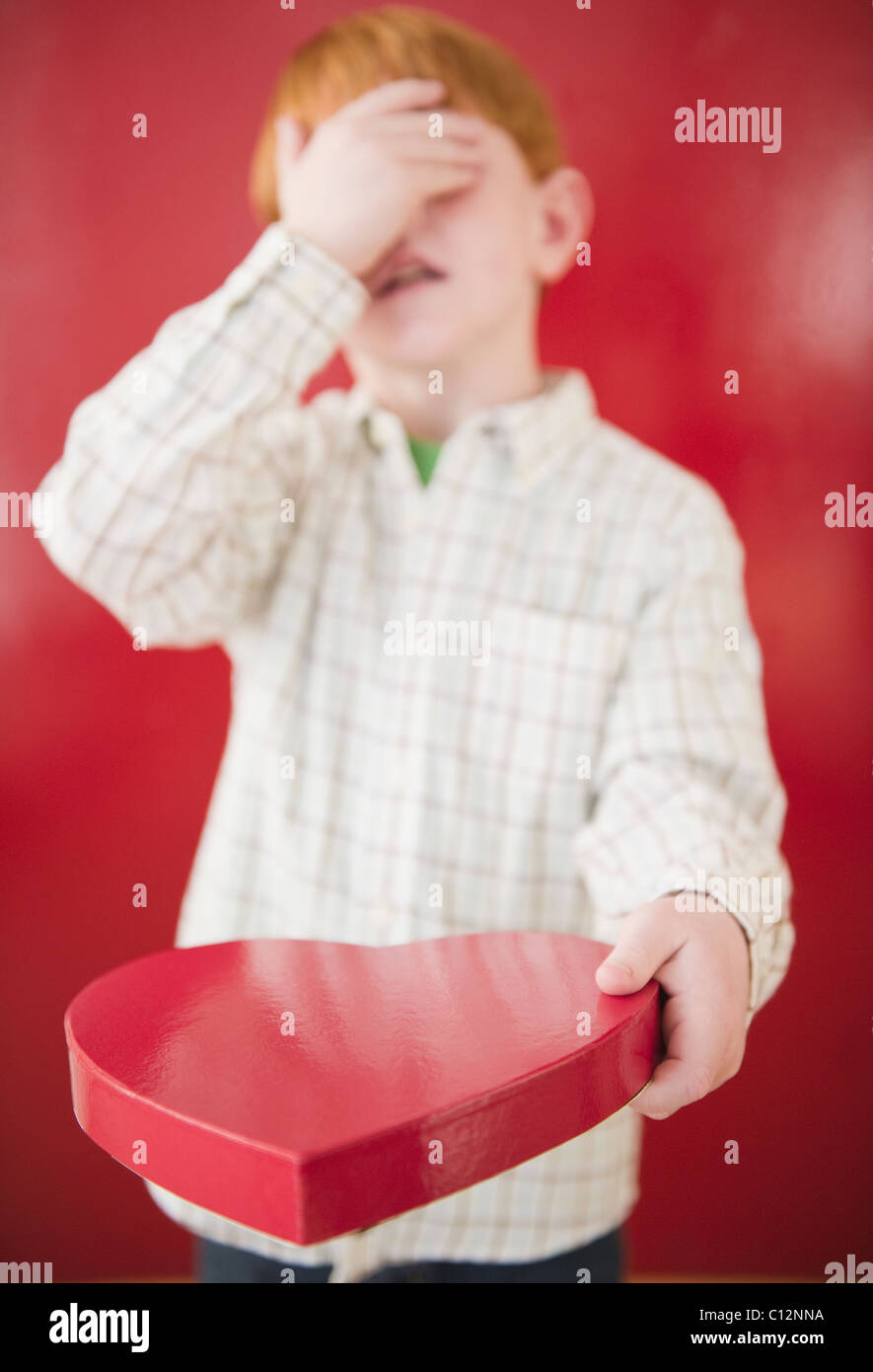 Ragazzo (8-9) di fissaggio scatola di cioccolatini per San Valentino Foto Stock