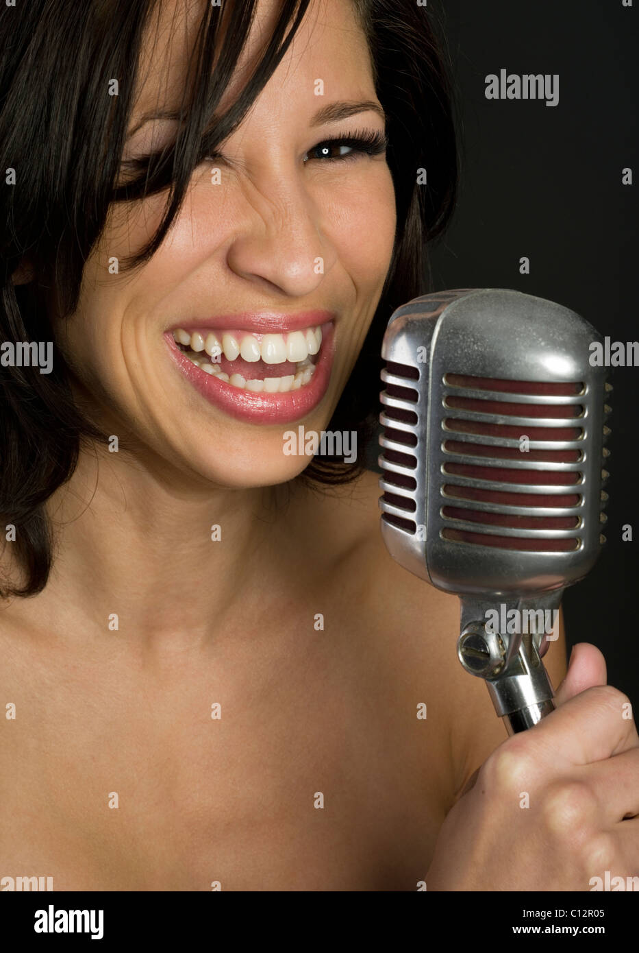 Bella donna con microfono cercando nella fotocamera e sorridente Foto Stock