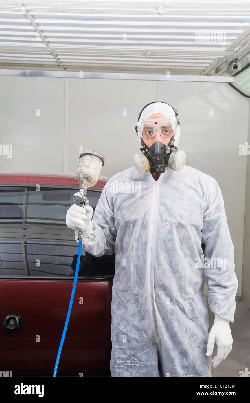 Meccanico automatico in possesso di una pistola di verniciatura a spruzzo in un garage Foto Stock