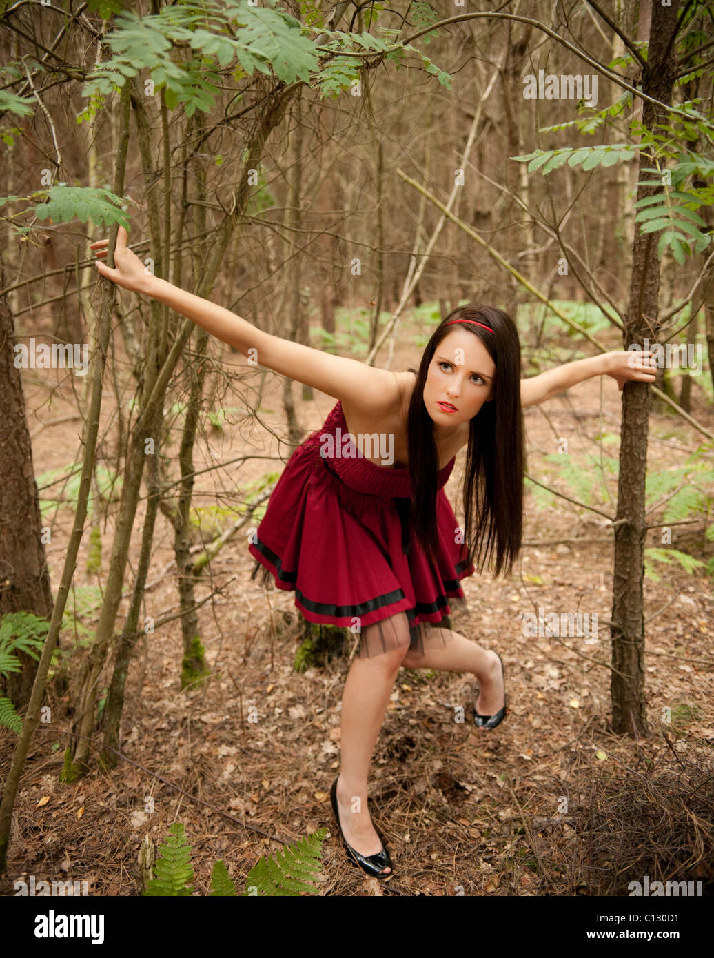 Giovane donna in abito rosso in una foresta Foto Stock