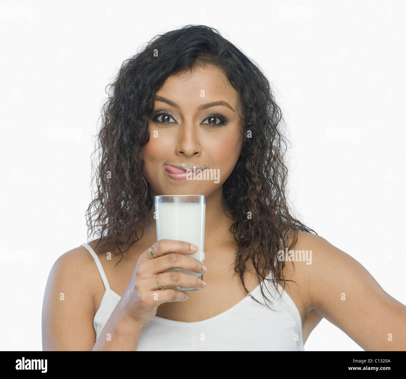 Donna che mantiene un bicchiere di latte e leccarsi le labbra Foto Stock