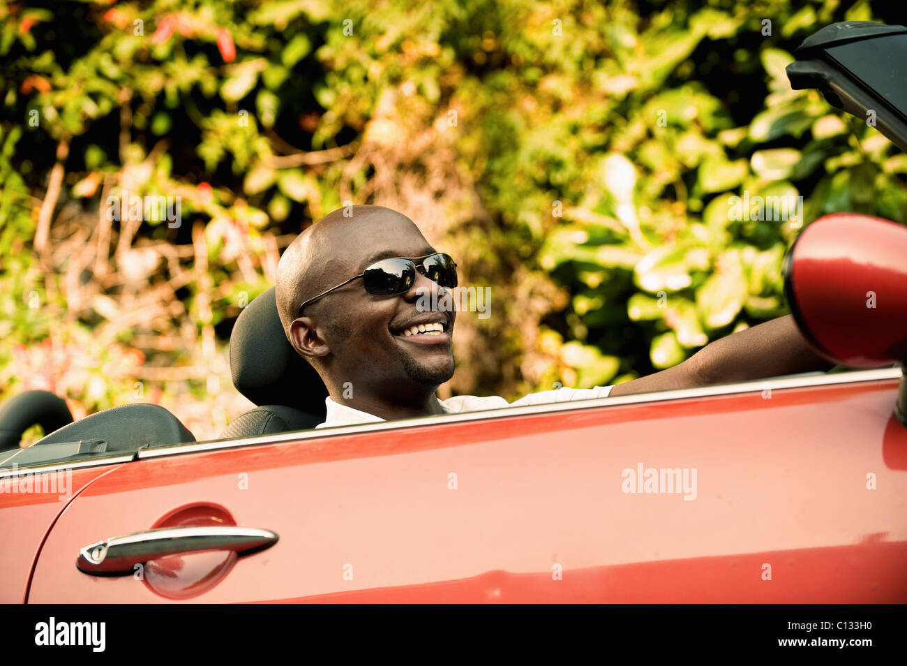 Giovane uomo sorridente come egli unità autovettura convertibile. Johannesburg, Sud Africa Foto Stock