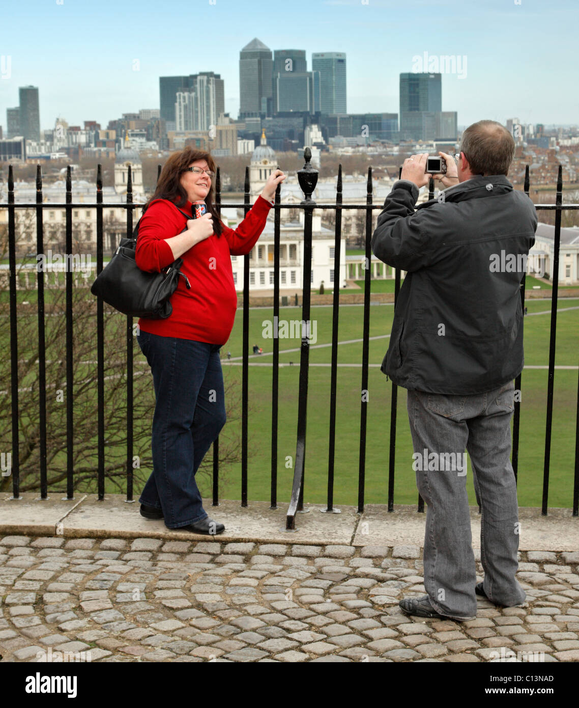 I turisti che posano per una foto di fronte a Canary Wharf, Londra. Foto Stock