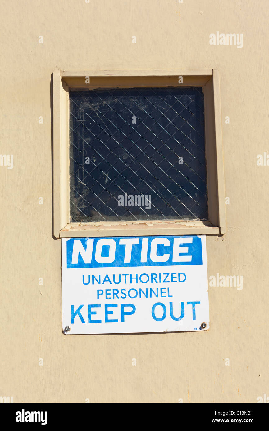 Un segno postato su una porta al di sotto di una maglia a filo finestra che recita: avviso personale non autorizzato tenere fuori. Foto Stock