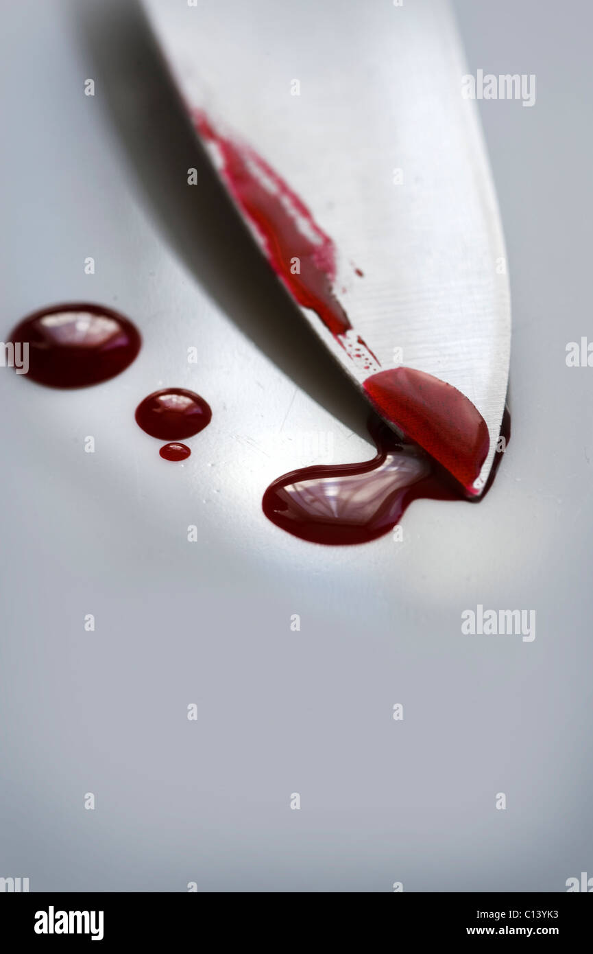 Lama di un coltello su una superficie bianca con gocce di sangue Foto Stock