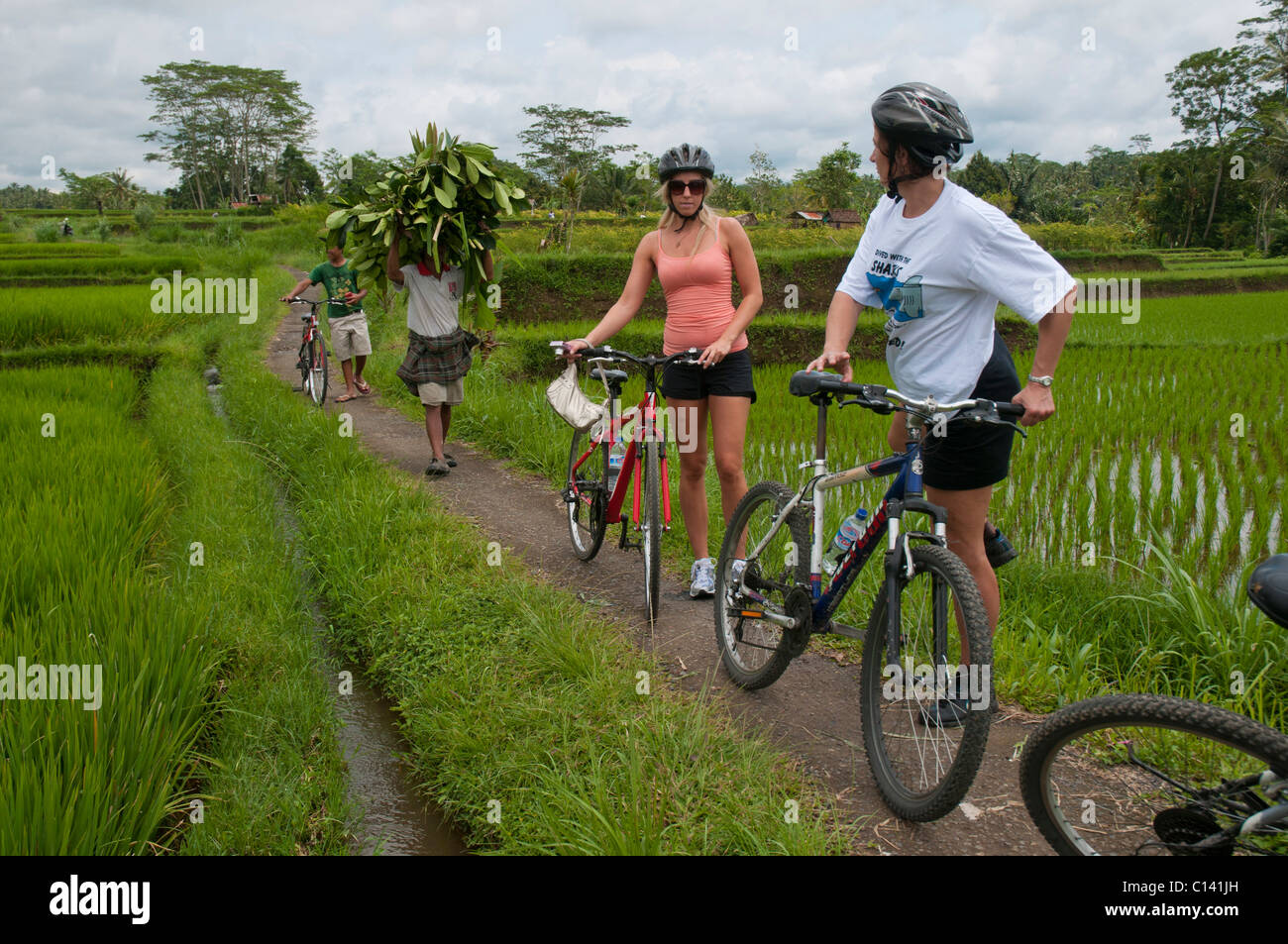 In mountain bike attraverso i villaggi e le risaie di Bali Indonesia Foto Stock
