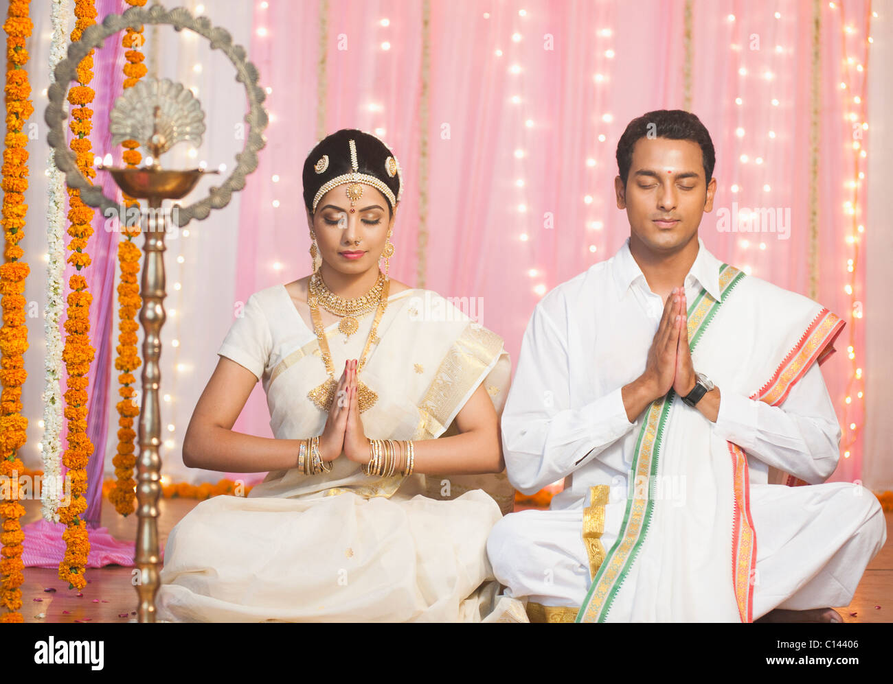 Sposa e lo sposo in Sud tradizionale abito indiano pregando alla cerimonia di nozze Foto Stock