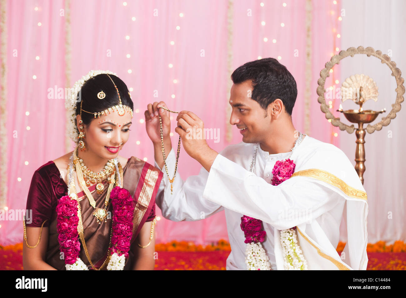 Sposo mettendo Mangal Sutra per una sposa al sud indiana cerimonia di nozze Foto Stock