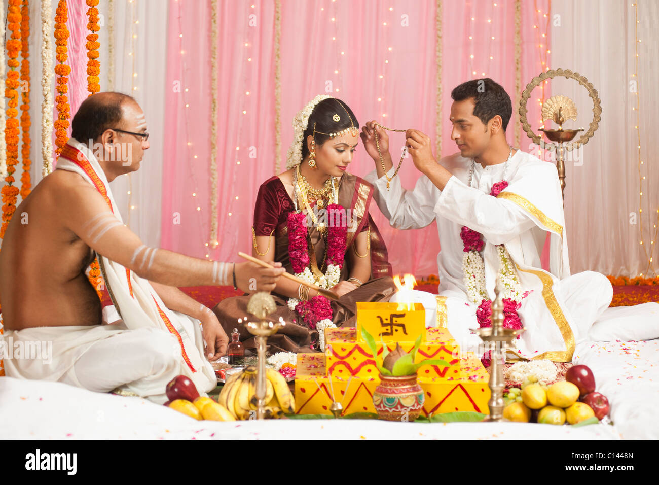 Sposo mettendo Mangal Sutra per una sposa al sud indiana cerimonia di nozze Foto Stock